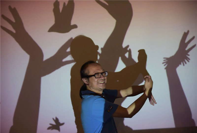 Shen Xiao en un espectáculo de sombras con manos en su estudio en Chengdu, provincia de Sichuan, el 20 de septiembre de 2014. 