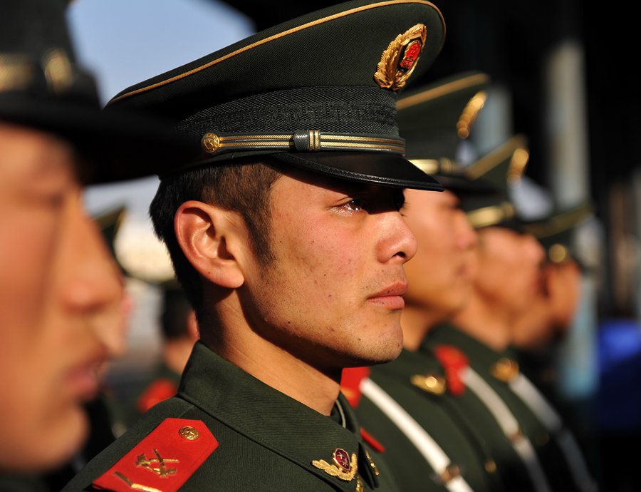 Un recluta observa, con lágrimas en sus ojos, como sus hermanos regresan a casa. Estación de ferrocarril de Chaoyang, Liaoning. [Foto: Xinhua]