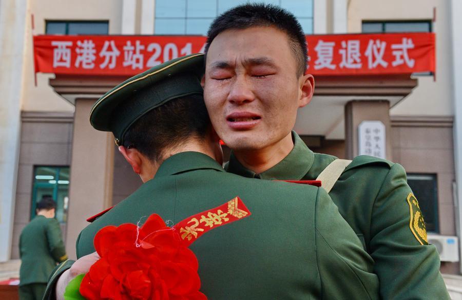 En el momento de despedirse y regresar a casa, un recluta abraza a su compa?ero de campa?a. [Foto: Xinhua]