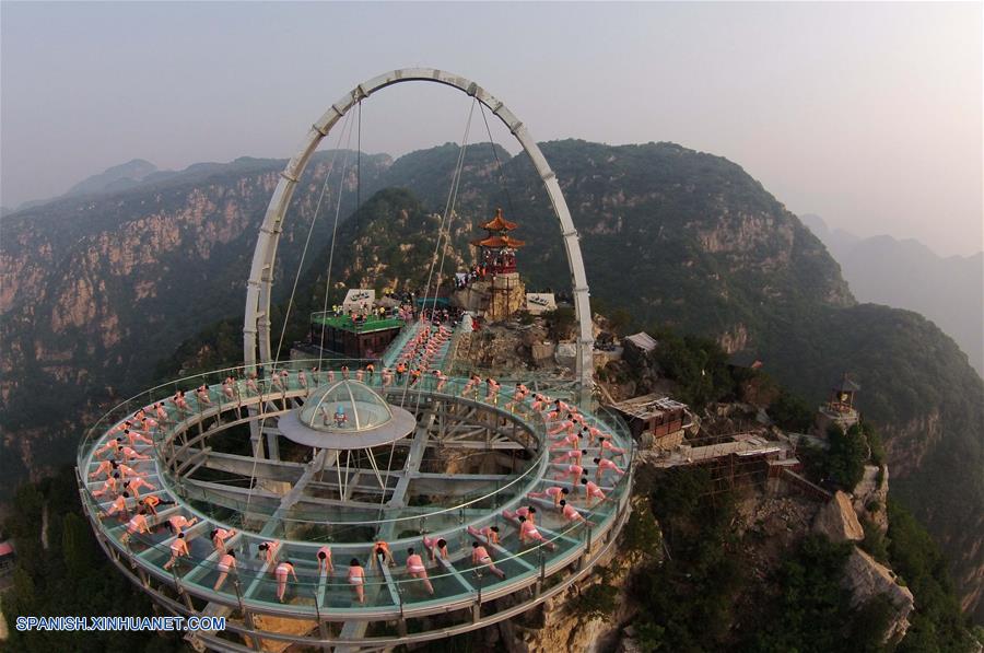 Personas practican yoga en una plataforma de cristal en Beijing