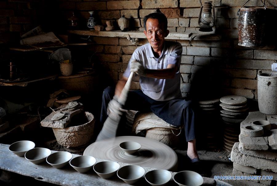 Imagen del 28 de junio de 2016 del artista folclórico Zhou Tiehuai elaborando cuencos de porcelana en bruto, en la zona turística de Yaotou Kiln en el municipio de Yaotou del condado de Chengcheng, provincia de Shaanxi, en el noroeste de China. El sitio de antiguos hornos populares, cubriendo un área de cuatro kilómetros cuadrados, tiene una historia de elaboración de productos de cerámica de más de mil a?os. La técnica de elaboración de cerámica en Yaotou Kiln fue incluida en el Patrimonio Nacional Cultural Intangible en el 2006. (Xinhua/Tao Ming)