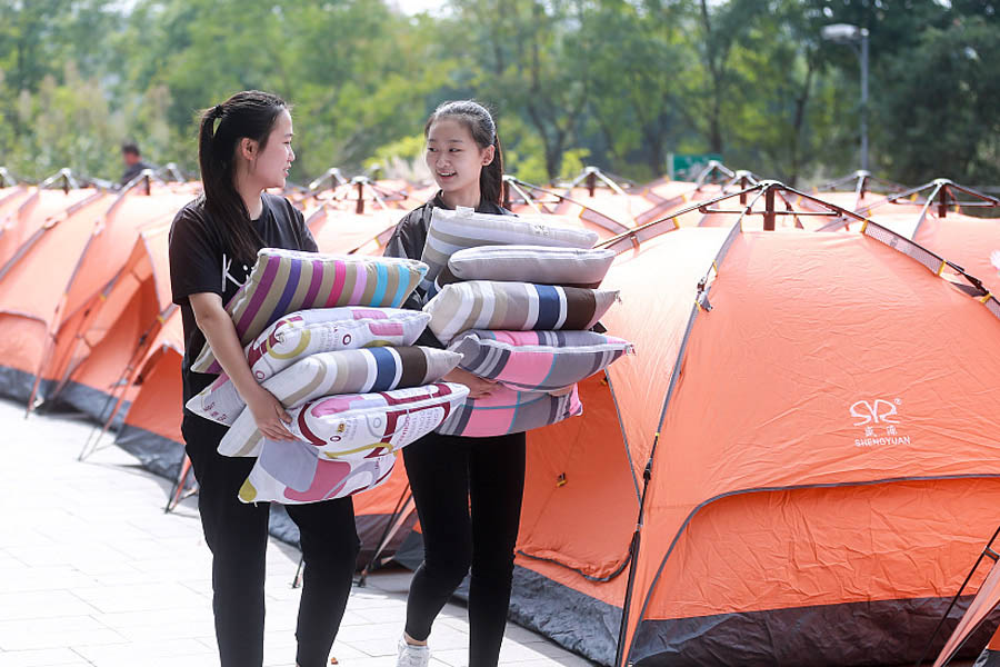Dos miembros del personal de apoyo suministran almohadas para las camas del campamento laboral del Festival de Compras 11-11 o Día del Soltero en la sede de Alibaba en Hangzhou, provincia de Zhejiang.31 de octubre del 2017. [Foto: VCG]