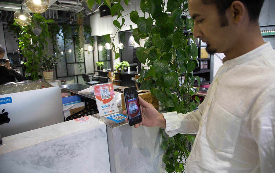 Nayeem Hafeez escanea un código bidimensional con su teléfono móvil para elegir su peluquero favorito en Hangzhou, provincia de Zhejiang, el 12 de noviembre de 2017. [Foto / VCG]