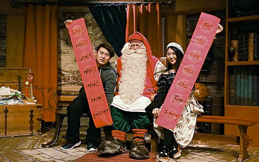 Viajeros chinos posan para una foto con Santa Claus junto a hermosos pareados (chunlian, en idioma chino), Rovaniemi, Finlandia, 7 de febrero del 2018. [Foto: VCG]