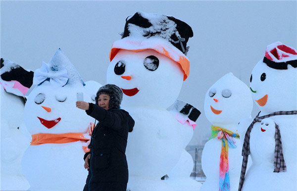 Un visitante posa junto a un gracioso mu?eco de nieve que se exhibe en el Parque del Hielo y la Nieve de Harbin, provincia de Heilongjiang, que atrae a muchos visitantes de diferentes latitudes de China. [Foto: IC]
