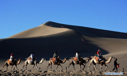 Los turistas visitan la Monta?a Mingsha y el Lago de la Luna Creciente en Gansu 