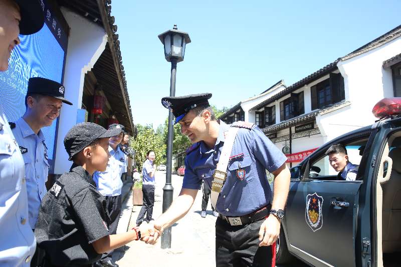 Un policía italiano estrecha la mano de un ni?o en la zona del Lago del Oeste, Hangzhou, capital de la provincia de Zhejiang. [Foto: proporcionada por la Oficina de Seguridad Pública de Hangzhou]