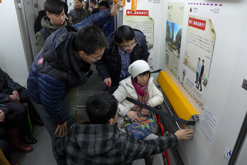 Voluntarios ayudan a una se?ora discapacitada en el metro de Shenyang, provincia de Liaoning. (Foto: Zhao Jingdong/ China Daily)