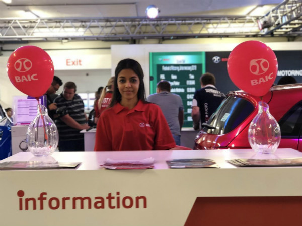 Una mujer posa en el mostrador de información del Grupo BAIC en el Salón del Automóvil de Sudáfrica celebrado en Johannesburgo. [Foto proporcionada a chinadaily.com.cn]