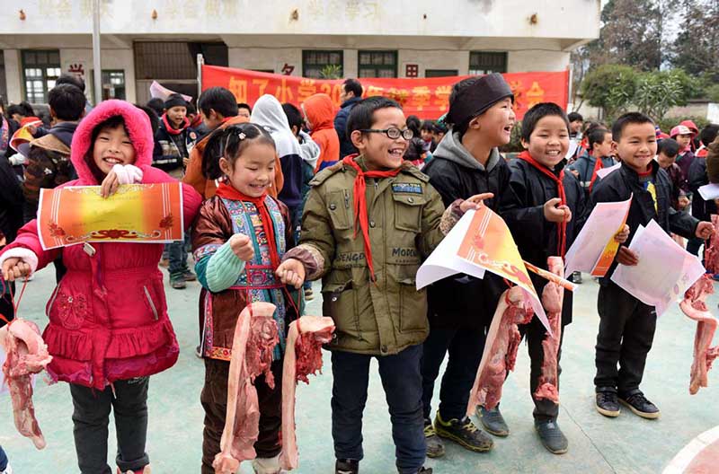 Los estudiantes de Grinning son galardonados con carne de cerdo por su buen desempe?o académico en una escuela primaria de Liuzhou, Región Autónoma Guangxi Zhuang. [Foto: Gong Pukang/ Chinadaily.com.cn]