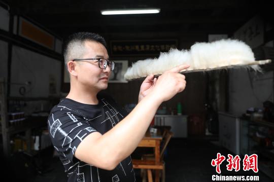 Jiang Guangming， un cocinero de este tipo de tofu, mide la longitud de los filamentos para determinar si el tofu ha fermentado completamente.[Foto: Fan Chengzhu/ Chinanews.com]