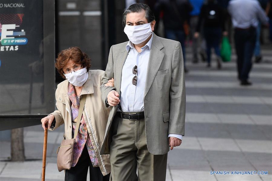 Personas portan mascarillas mientras caminan en una calle en Santiago, capital de Chile, el 21 de abril de 2020. Chile aumentó a 10.832 el número de casos de la enfermedad causada por el nuevo coronavirus (COVID-19), de los cuales 147 han muerto, informó el martes el Ministerio de Salud del país. (Xinhua/Jorge Villegas)