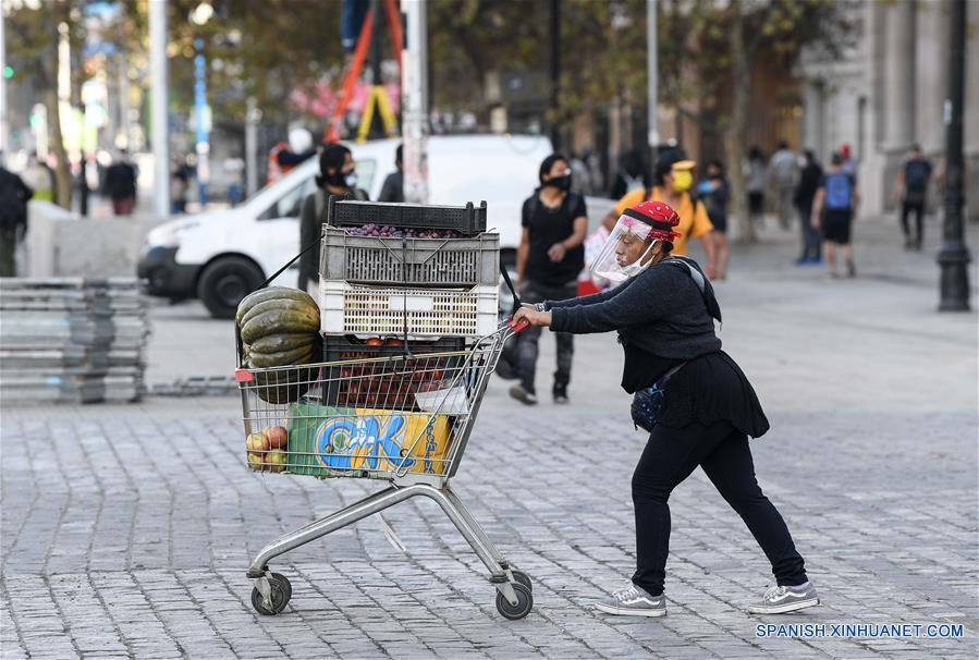 Una mujer porta una mascarilla mientras traslada verduras en una calle en Santiago, capital de Chile, el 21 de abril de 2020. Chile aumentó a 10.832 el número de casos de la enfermedad causada por el nuevo coronavirus (COVID-19), de los cuales 147 han muerto, informó el martes el Ministerio de Salud del país. (Xinhua/Jorge Villegas)