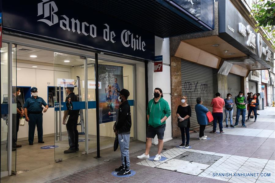 Personas portan mascarillas mientras se forman manteniendo distancia social para ingresar a una sucursal bancaria en Santiago, capital de Chile, el 21 de abril de 2020. Chile aumentó a 10.832 el número de casos de la enfermedad causada por el nuevo coronavirus (COVID-19), de los cuales 147 han muerto, informó el martes el Ministerio de Salud del país. (Xinhua/Jorge Villegas)