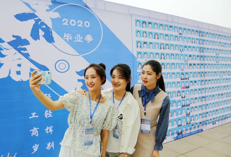 Graduados del Colegio Vocacional Nantong de Ciencia y Tecnología, en la provincia de Jiangsu, posan para una foto frente a una placa, 16 de mayo del 2020. (Foto: Feng Kaimin/ Pueblo en Línea)