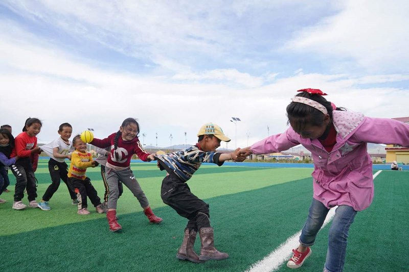 Ni?os juegan en un campo de fútbol en la Aldea Cultural Amdo, un proyecto de reasentamiento para familias pobres, en el condado Xinghai, provincia de Qinghai. [Foto de Feng Yongbin / China Daily]