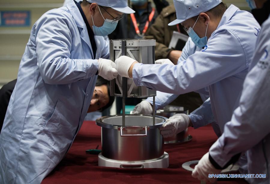 Imagen del 17 de diciembre de 2020 de investigadores científicos transfiriendo el contenedor cargado con muestras lunares, en Beijing, capital de China. La sonda espacial Chang'e-5 de China trajo a la Tierra alrededor de 1.731 gramos de muestras tomadas en la Luna, según informó la Administración Nacional del Espacio de China. Los científicos llevarán a cabo el almacenamiento, análisis e investigación de las primeras muestras lunares recolectadas por China. (Xinhua/Jin Liwang)