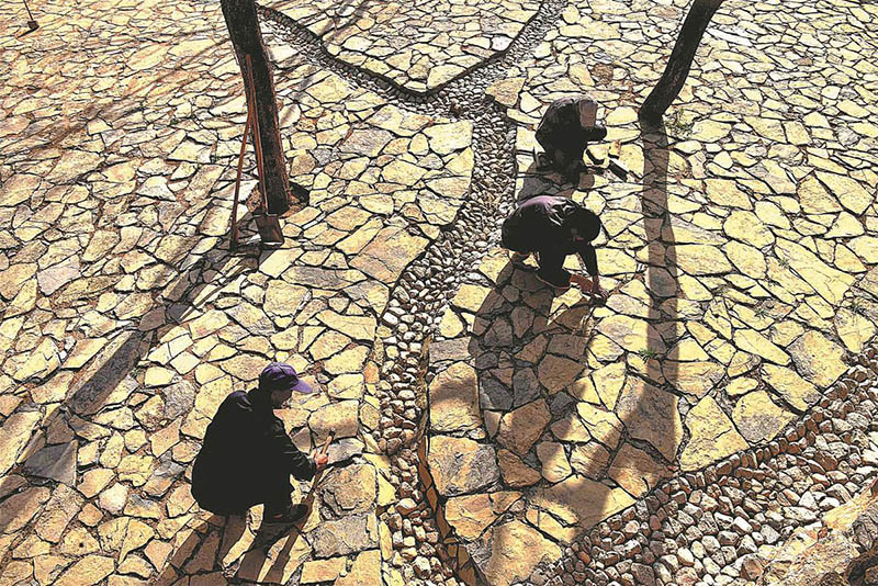 Los aldeanos se ofrecen como voluntarios para pavimentar una plaza con piedras. [Foto de Zhao Dongshan y Fu Youmin / para China Daily]