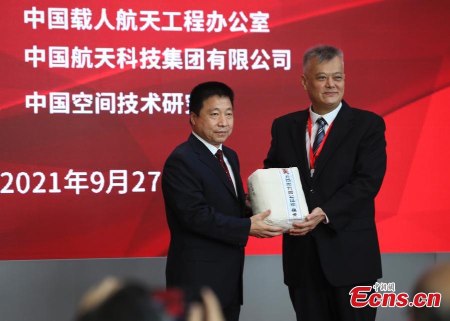 El primer astronauta de China, Yang Liwei, entrega los artículos extraídos de la cápsula a un representante de China Post Group Corp, durante la ceremonia de apertura de la cápsula de retorno de la nave espacial Shenzhou-12, Beijing, 27 de septiembre del 2021. (Servicio de Noticias de China/ Zhao Jun)