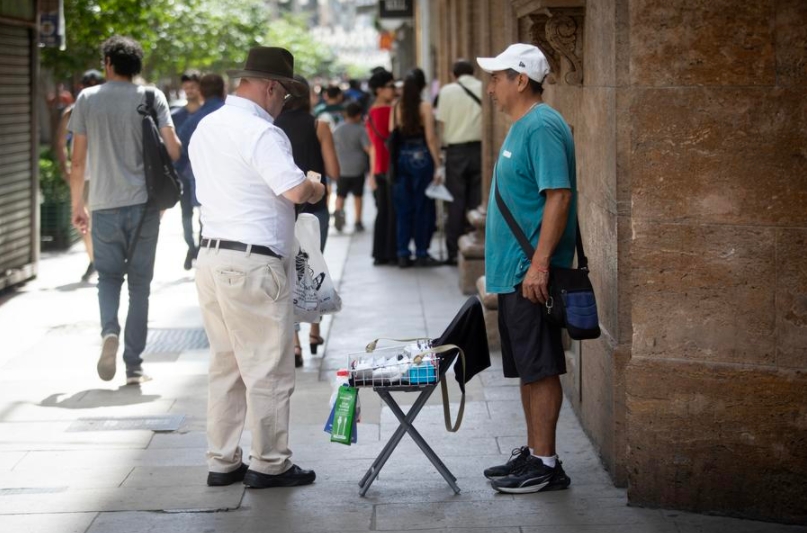 Un vendedor ambulante ofrece sus productos a un hombre en una calle, en Buenos Aires, capital de Argentina, el 21 de marzo de 2025. (Xinhua/Martín Zabala) 
