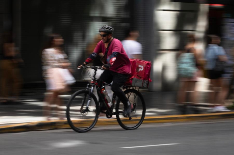 Un trabajador de una aplicación de mensajería conduce su bicicleta por una calle, en Buenos Aires, capital de Argentina, el 21 de marzo de 2025. (Xinhua/Martín Zabala)