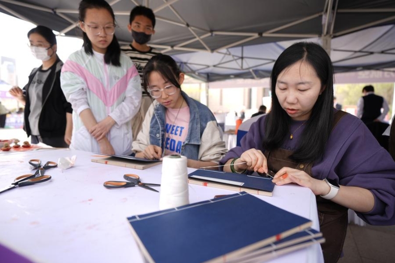 Personas experimentan la encuadernación con puntadas, una práctica tradicional china, durante un evento de lectura en Yinchuan, en la región autónoma de la etnia hui de Ningxia, en el noroeste de China, el 20 de abril de 2025. (Xinhua/Wang Peng)