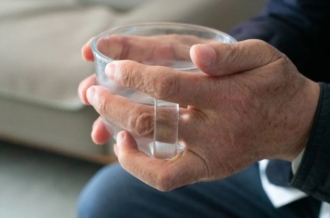 Una persona mayor sostiene un vaso de vidrio transparente. (Xinhua)