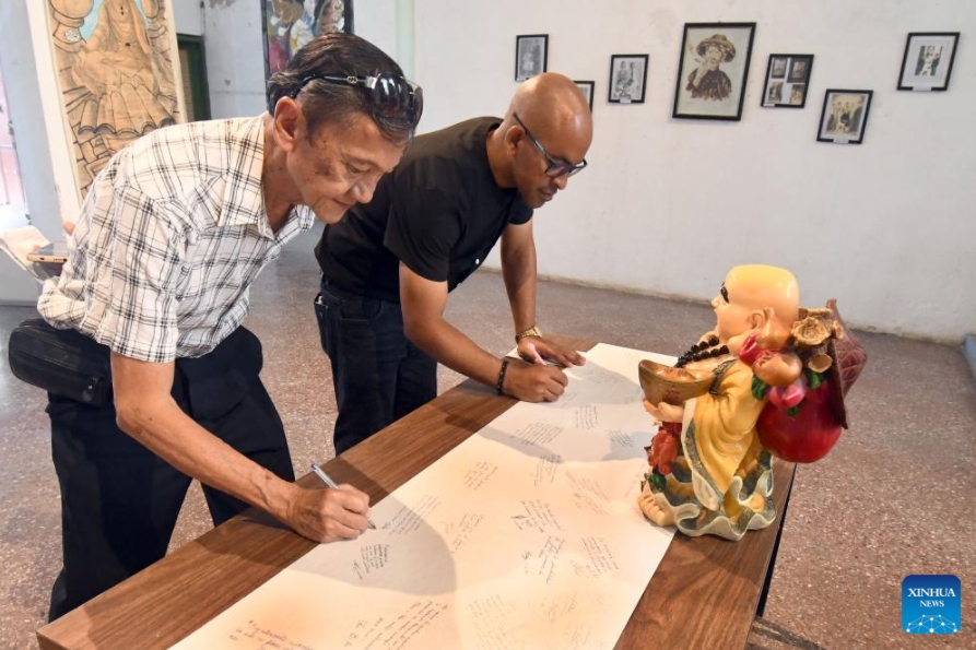 Personas escriben sus impresiones sobre la exposición "Raíces en el Caribe. Familias sino-cubanas: tradición y fusión" en la Casa de las Artes y Tradiciones Chinas, en el Barrio Chino de La Habana, capital de Cuba, el 11 de junio de 2025. El Barrio Chino de La Habana recordó con la apertura de una exposición fotográfica la llegada a Cuba hace 178 a?os de los primeros culíes, quienes dejaron una profunda huella en la historia y en la formación de la nacionalidad cubana. (Xinhua/Joaquín Hernández)