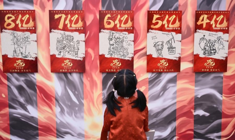 Una ni?a observa copias de carteles dibujados a mano del éxito de taquilla animado chino "Ne Zha 2" en una exposición celebrada en Beijing, capital de China, el 19 de abril de 2025. (Xinhua/Li Xin)