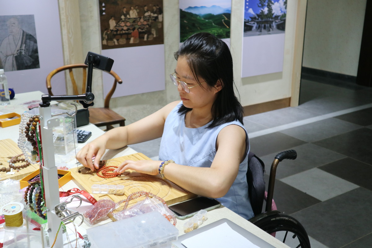 Zhang Ruixia elabora una pulsera en la tienda de artesanías de Jingshan, provincia de Zhejiang, el 5 de agosto. [Foto de Li Menghan/chinadaily.com.cn]