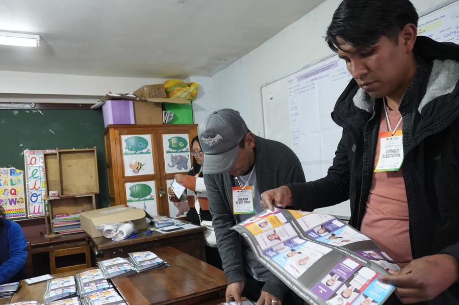 Un funcionario electoral (d), muestra una boleta electoral, mientras se realiza el conteo de votos al término de las elecciones generales, en una unidad educativa, en la ciudad de La Paz, Bolivia, el 17 de agosto de 2025. (Xinhua/Javier Mamani)