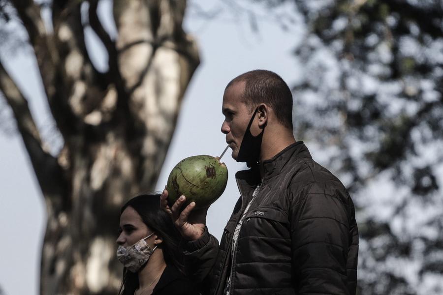 Un hombre bebe agua de coco en el parque Ibirapuera, en Sao Paulo, Brasil, el 23 de julio de 2021. (Xinhua/Rahel Patrasso)