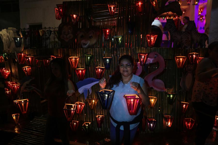 Imagen del 7 de septiembre de 2025 de una mujer sosteniendo faroles en la estructura de una vivienda durante la festividad del Día de los Farolitos, en el municipio de Concepción de Ataco, en el departamento de Ahuachapán, El Salvador. (Xinhua/Alexander Pe?a)