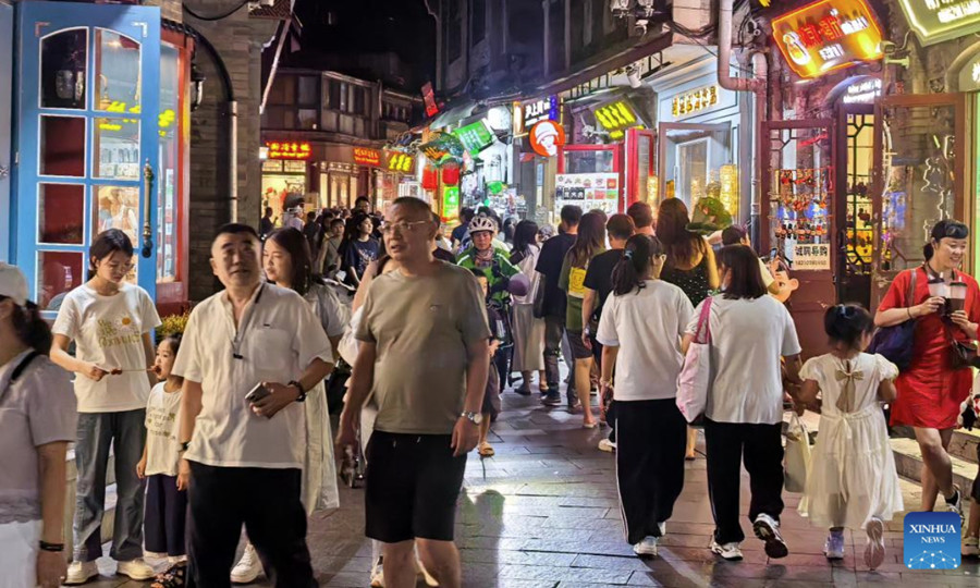 Personas caminan por una calle peatonal cerca del área escénica de Shichahai en Beijing, capital de China, el 30 de julio de 2025. Bejing ha desarrollado vigorosamente su economía nocturna desde principios de este verano, ofreciendo gastronomía local, cine al aire libre, festivales de música y mercados nocturnos. (Xinhua/Li Xin)