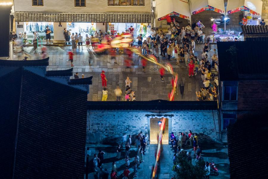 Esta foto aérea, tomada el 5 de octubre de 2025, muestra grupos de personas observando un desfile de dragones en bancos de madera, en el distrito de Pujiang de la provincia oriental china de Zhejiang. (Xinhua/Zhang Hui)