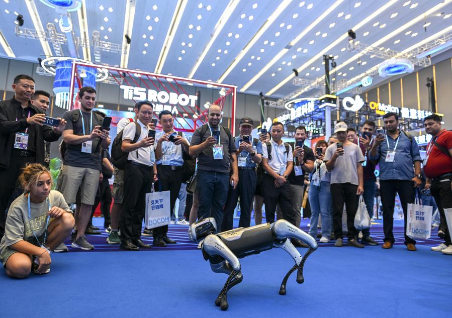 Visitantes observan una actuación realizada por un perro robot en un espacio de la empresa MagicLab Robotics Technology Co., Ltd. en la Zona de Robots de Servicios durante la edición número 138 de la Feria de Importación y Exportación de China (Feria de Cantón) en Guangzhou, provincia de Guangdong, en el sur de China, el 15 de octubre de 2025. (Xinhua/Xiao Ennan)