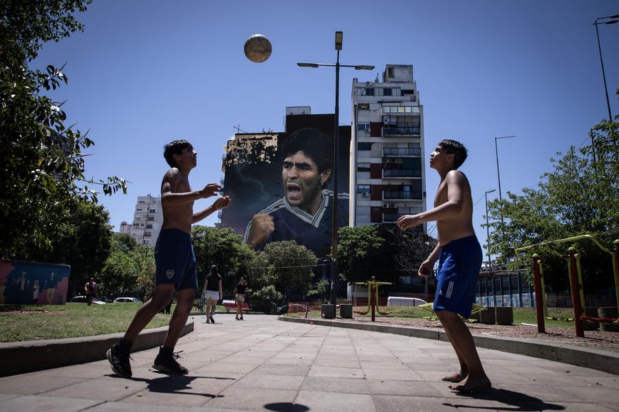 Imagen del 24 de noviembre de 2023 de jóvenes jugando al fútbol frente a un mural en homenaje al futbolista Diego Armando Maradona, en la ciudad de Buenos Aires, Argentina. (Xinhua/Martín Zabala) 
