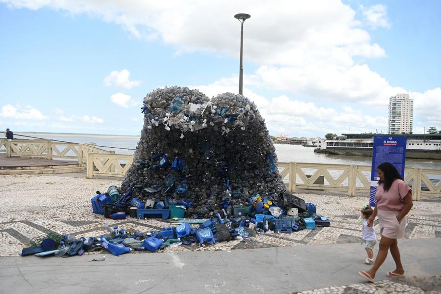 Una mujer camina cerca de una escultura con forma de ola hecha de materiales plásticos en las orillas del río Guamá, previo a la apertura de la 30a Conferencia de las Partes (COP30) de las Naciones Unidas sobre el Cambio Climático, en Belém, estado de Pará, Brasil, el 9 de noviembre de 2025. (Xinhua/Lucio Tavora) 