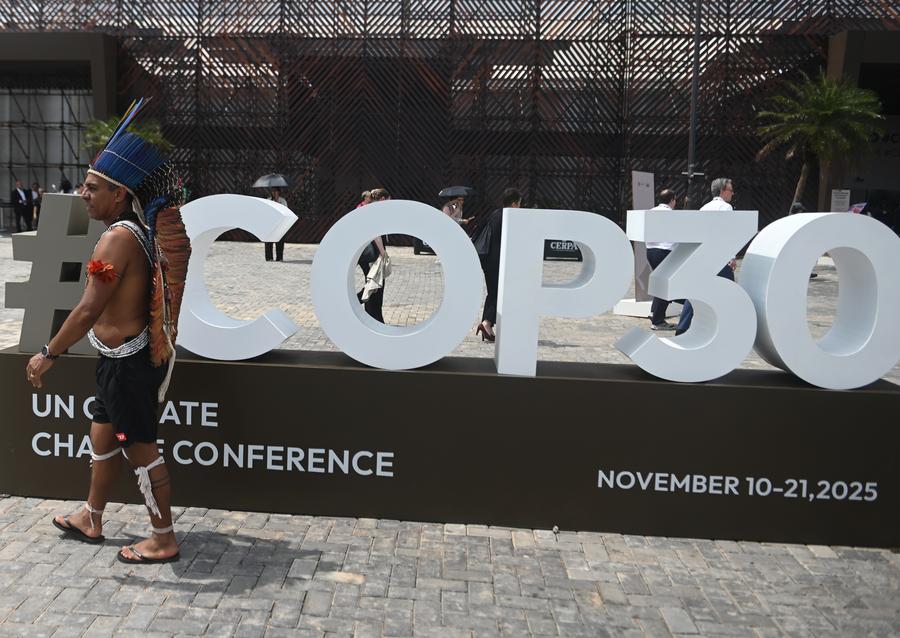 Un indígena camina frente al logotipo de la 30a Conferencia de las Partes (COP30) de la Convención Marco de las Naciones Unidas sobre el Cambio Climático, en Belém, en estado de Pará, Brasil, el 11 de noviembre de 2025. (Xinhua/Lucio Tavora)