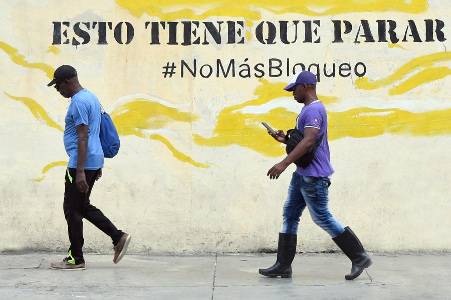 Imagen del 22 de septiembre de 2025 de personas caminando frente a un mural en contra del bloqueo económico de Estados Unidos impuesto a Cuba, en La Habana, capital de Cuba. (Xinhua/Joaquín Hernández) 